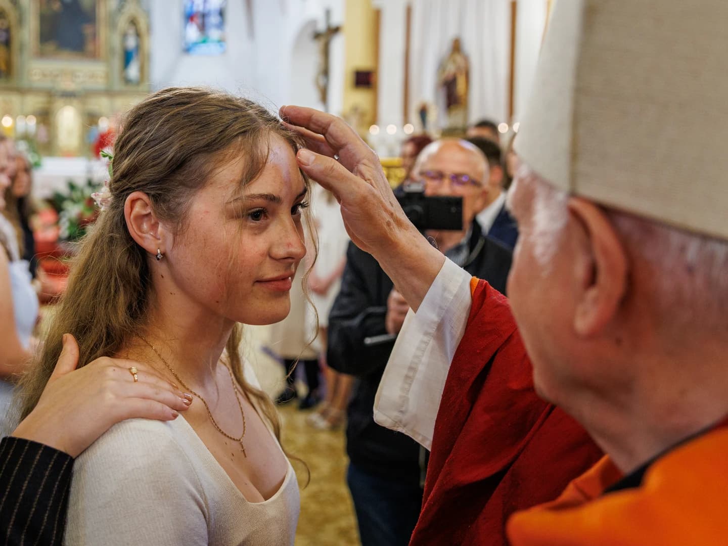 Biskup při biřmování pomazává čelo biřmovance křižmem