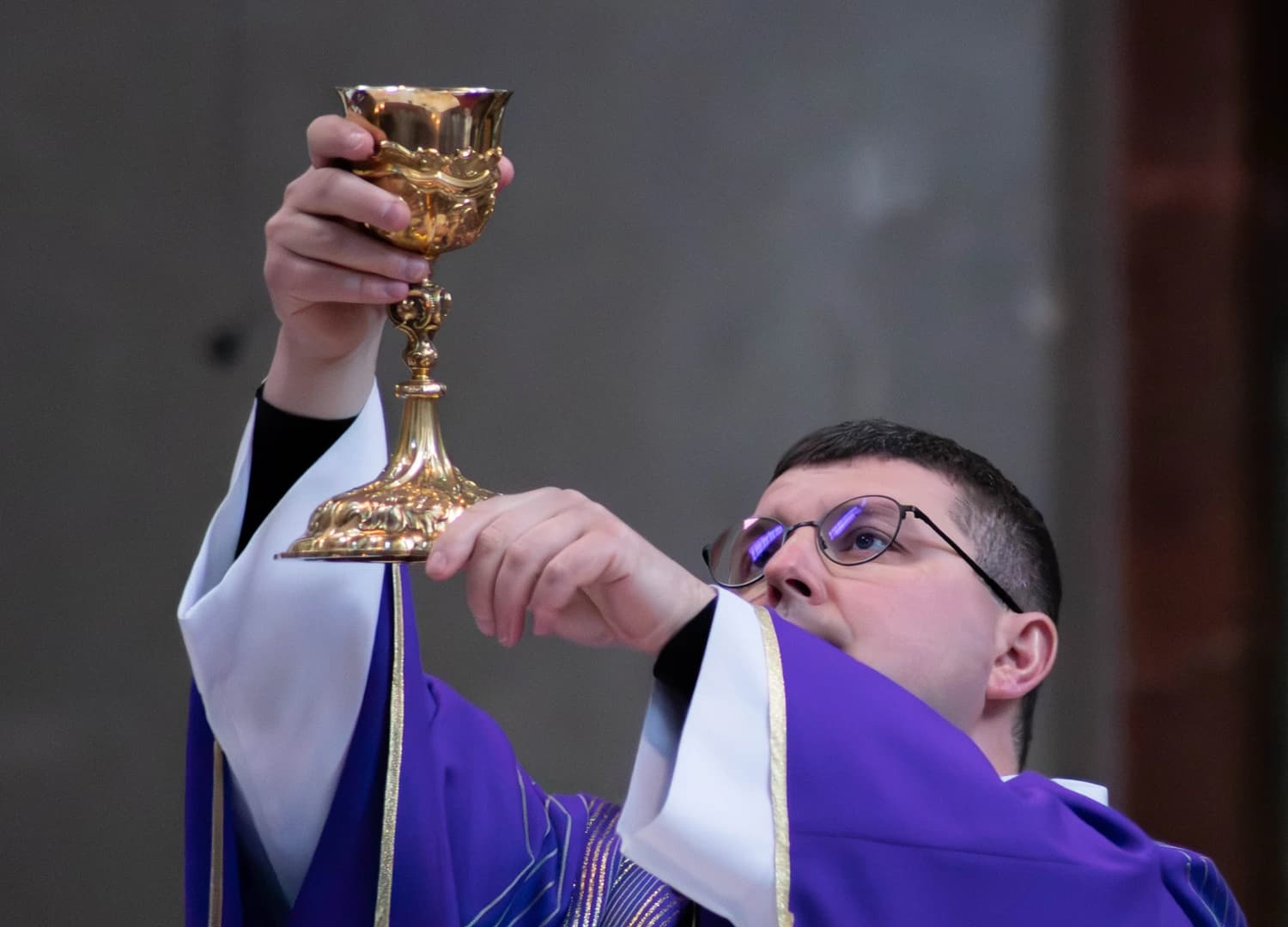 Kněz pozvedá kalich při mši
